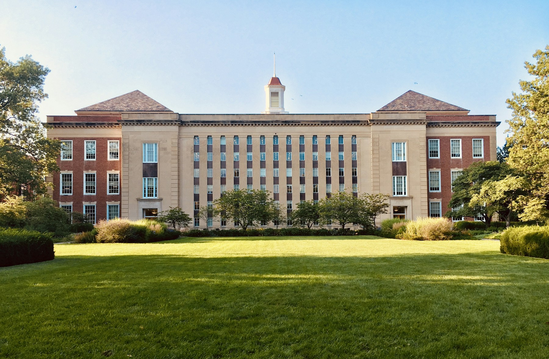 A classical university building surrounded by mature trees