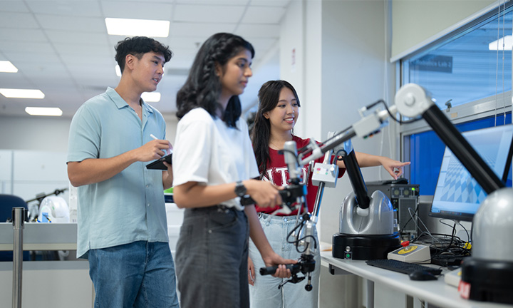 Students working with a robotic arm in a university laboratory